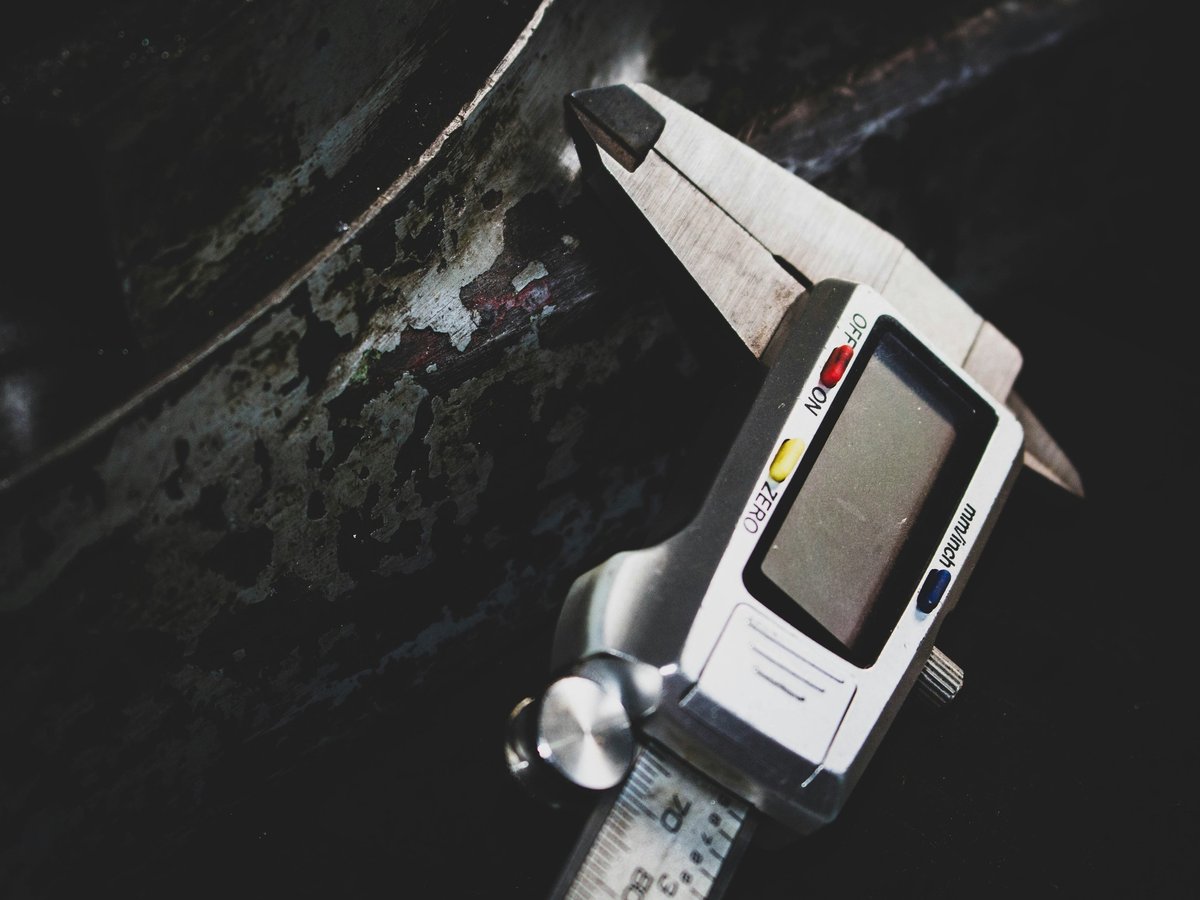 Overhead view of a digital caliper measuring an object against a dark background